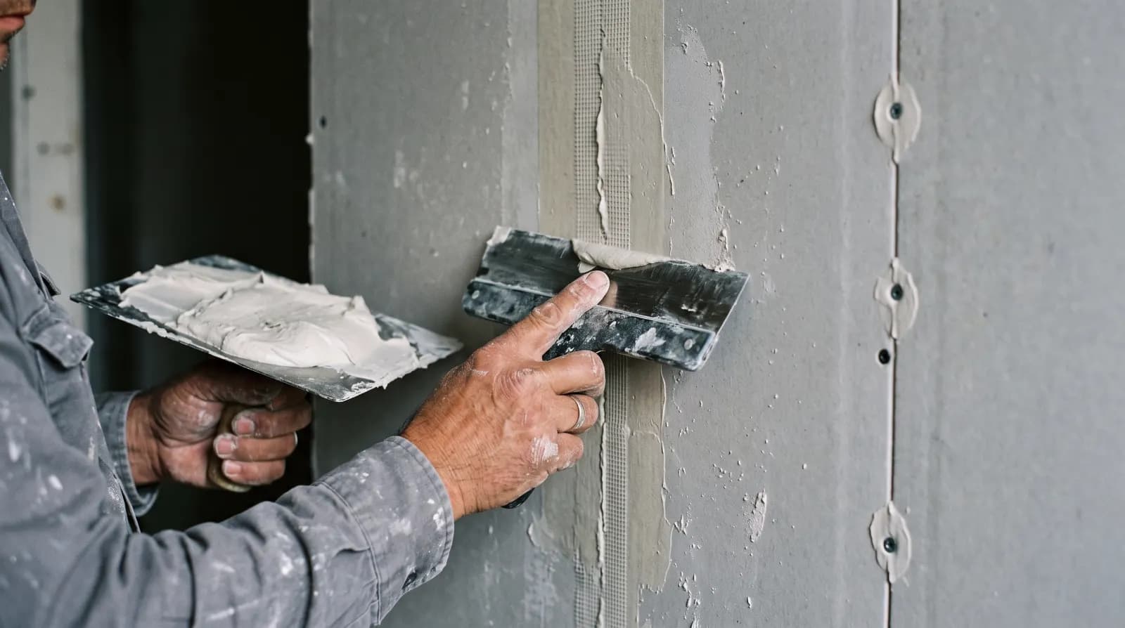 Application de la bande à joint sur un raccord de plaques, couteau à enduire
